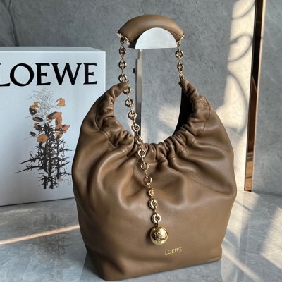 Loewe羅意威 現款Squeeze腋下包包上市啦 這款包以其褶設計感的Hobo造型展現出高級慵懶感和柔和的女性魅力，由Nappa帕羊皮製成，包身柔軟絲滑，光澤閃亮如綢緞，金色圓形小球的點綴，與觸感絲滑的皮革相得益彰 其特色在於甜甜圈形狀的